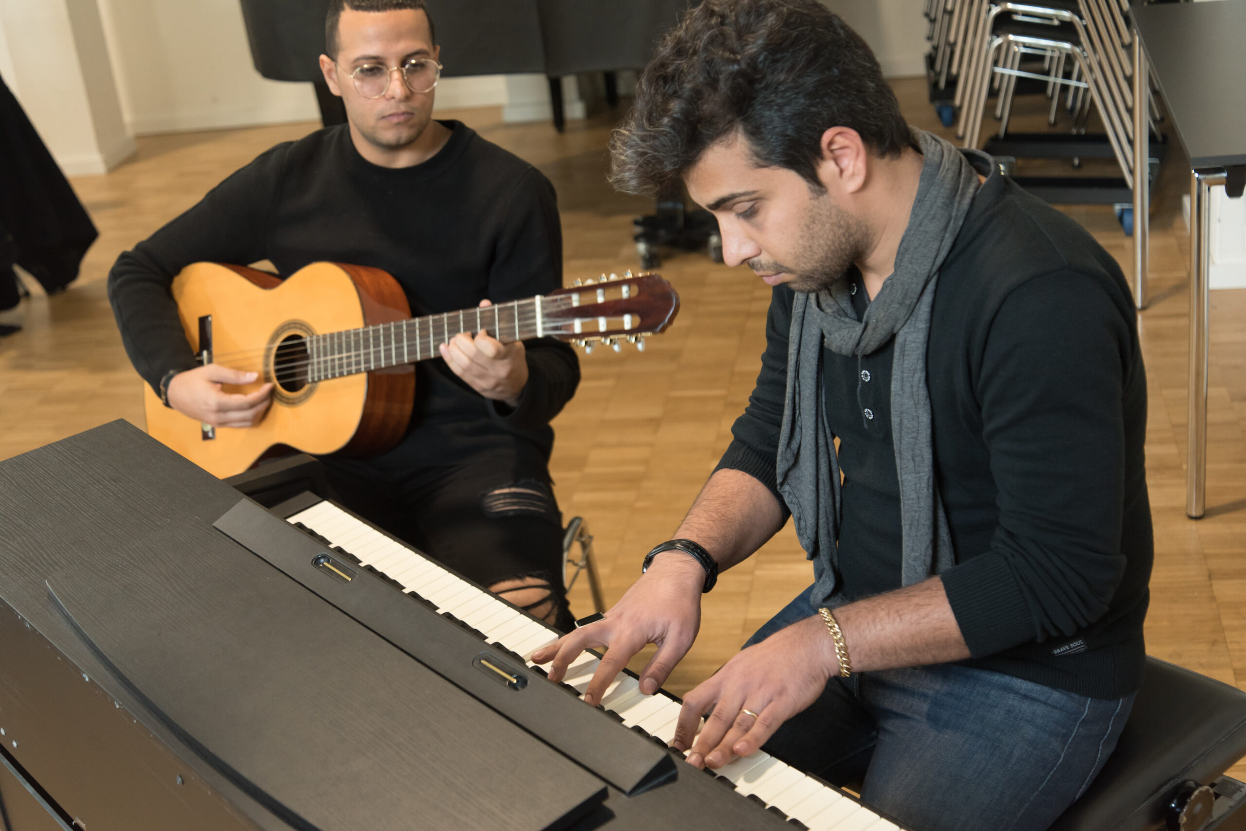 Ein Foto von einem Mann, der bei einem Projekt von International Music Education Klavier spielt, während ihn ein weiterer auf der Gitarre begleitet.